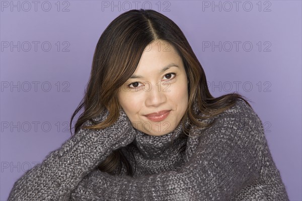 Portrait of smiling woman on purple background, studio shot. Photo : Rob Lewine