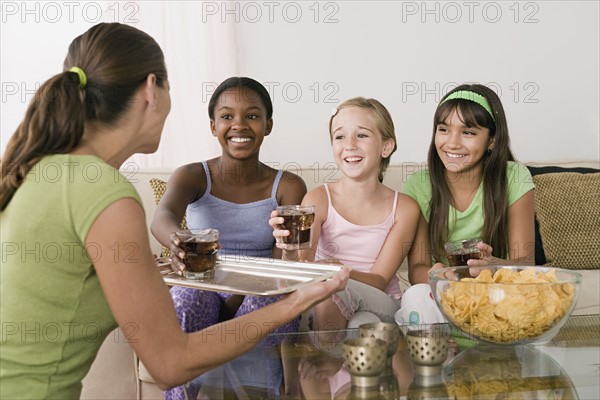 Woman serving drinks for three girls (10-11) at slumber party. Photo: Rob Lewine