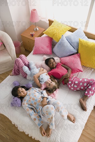 Three girls (10-11) lying on bed at slumber party. Photo : Rob Lewine