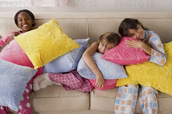 Portrait of three girls (10-11) lying on sofa at slumber party. Photo: Rob Lewine