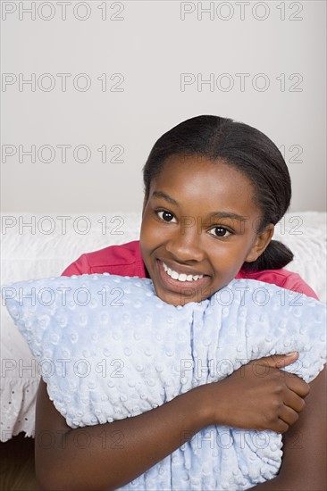 Portrait of smiling girl (10-11) with pillow. Photo: Rob Lewine