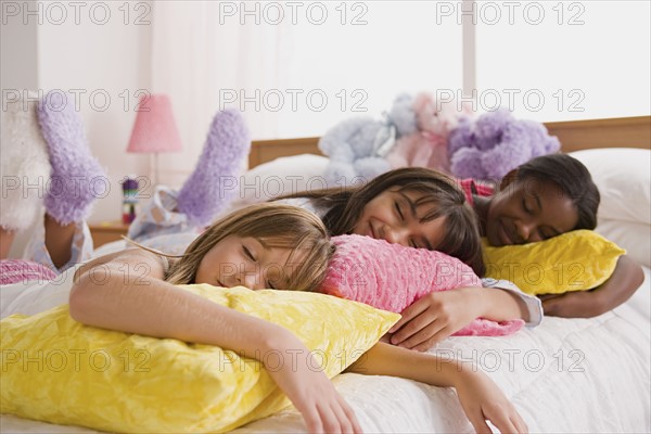 Three girls (10-11) sleeping on bed at slumber party. Photo : Rob Lewine