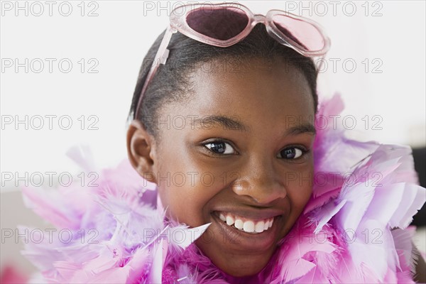 Portrait of smiling girl (10-11) wearing feather boa and sunglasses. Photo: Rob Lewine