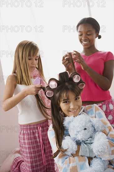 Three girls (10-11) doing hair at slumber party. Photo : Rob Lewine