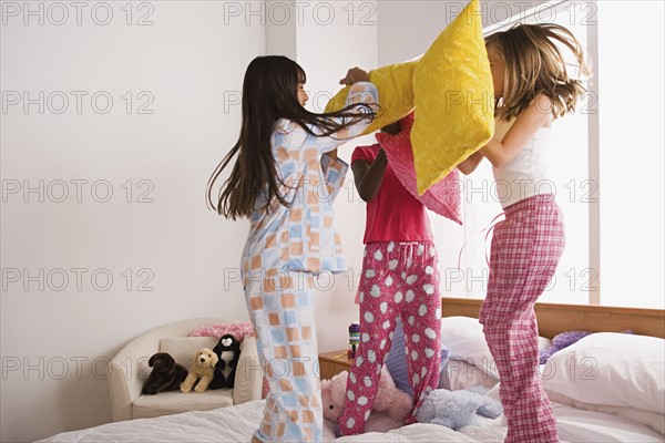 Three girls (10-11) having pillow fight at slumber party. Photo : Rob Lewine