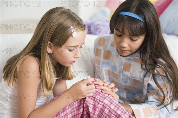Girl (10-11) painting fingernails of her friend at slumber party. Photo: Rob Lewine