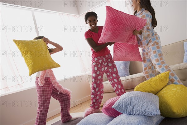 Three girls (10-11) having pillow fight at slumber party. Photo : Rob Lewine