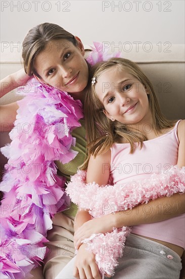 Portrait of mother and daughter (10-11) wearing feather boa at slumber party. Photo : Rob Lewine