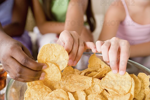 Three girls (10-11) reaching for crisps. Photo : Rob Lewine