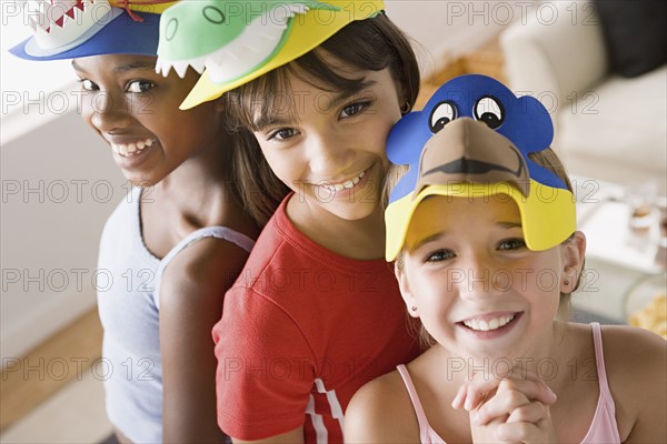 Portrait of three girls (10-11) wearing funny hats at slumber party. Photo: Rob Lewine