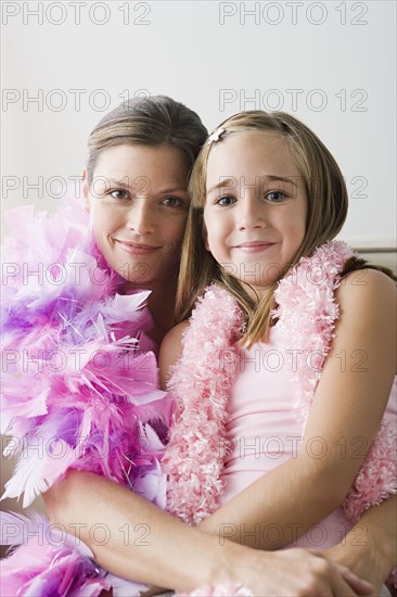 Portrait of mother and daughter (10-11) wearing feather boa at slumber party. Photo: Rob Lewine