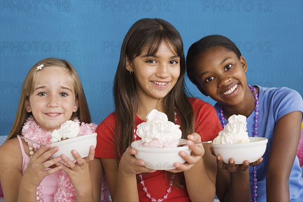 Portrait of three girls (10-11) holding desserts. Photo : Rob Lewine