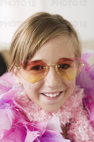 Portrait of smiling girl (10-11) wearing feather boa and sunglasses. Photo : Rob Lewine