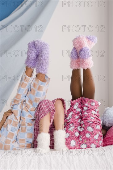 Close op of legs of three girls (10-11) lying on bed with feet up. Photo : Rob Lewine