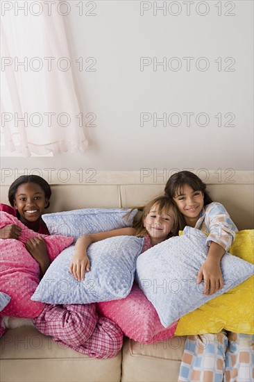 Portrait of three girls (10-11) lying on sofa at slumber party. Photo : Rob Lewine