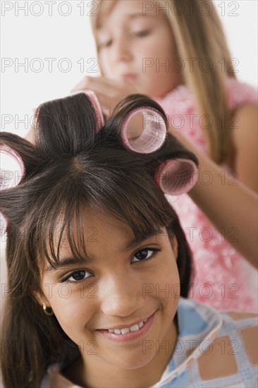 Portrait of girl (10-11) with curlers and another girl (10-11) in background. Photo : Rob Lewine