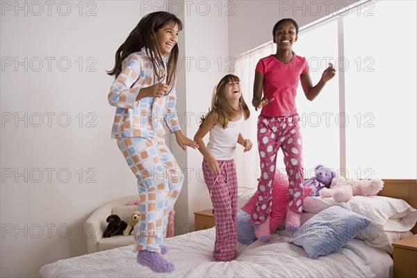 Three girls (10-11) jumping on bed at slumber party. Photo: Rob Lewine