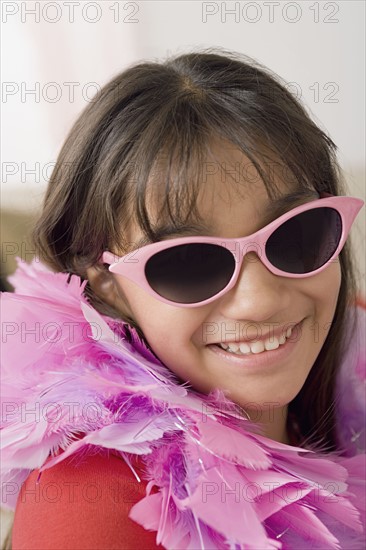 Portrait of smiling girl (10-11) wearing feather boa and sunglasses. Photo : Rob Lewine