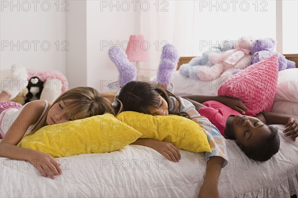 Three girls (10-11) sleeping on bed at slumber party. Photo: Rob Lewine