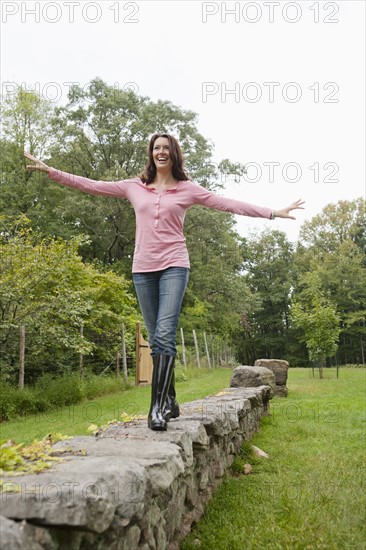 USA, New Jersey, Woman balancing on stone wall. Photo: Tetra Images