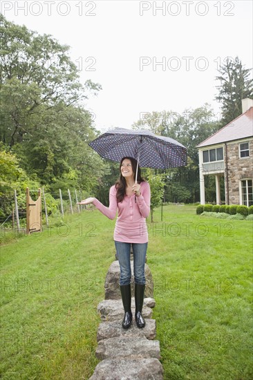 USA, New Jersey, Woman holding umbrella in backyard. Photo : Tetra Images