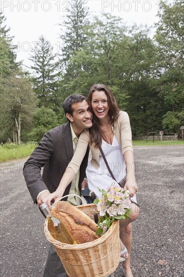 Portrait of couple on bike with basket. Photo: Tetra Images