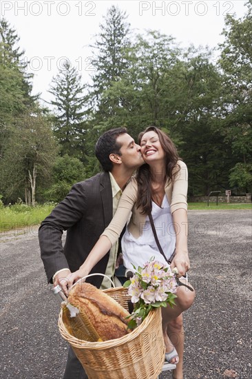 Portrait of couple on bike with basket. Photo: Tetra Images