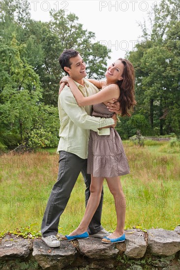 USA, New Jersey, Happy couple embracing on stone wall. Photo : Tetra Images