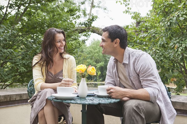 Happy couple sitting at table at outdoor cafe. Photo : Tetra Images