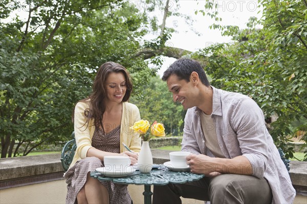 Happy couple sitting at table at outdoor cafe. Photo: Tetra Images