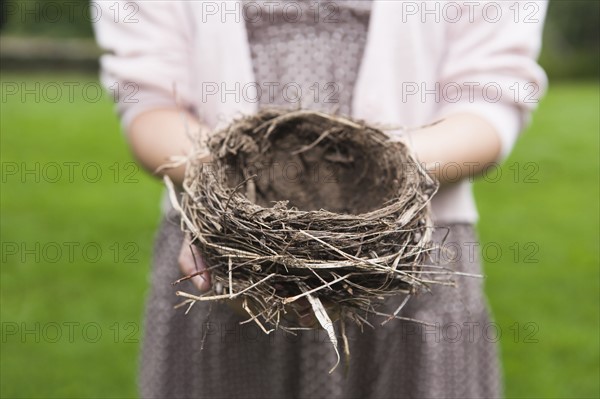 Happy woman standing on stone wall on field. Photo: Tetra Images