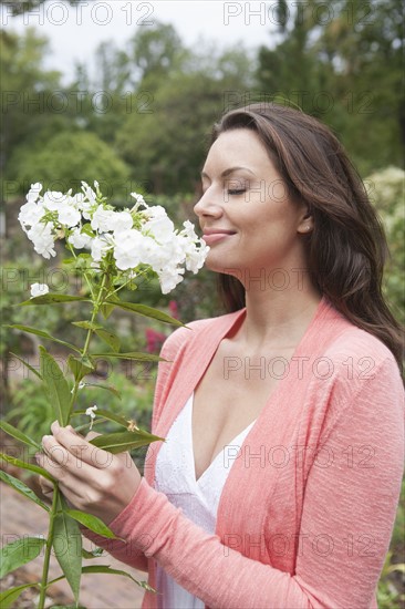 Smiling woman smelling white flowers. Photo : Tetra Images