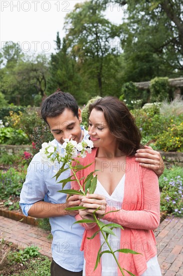 Happy couple smelling white flowers. Photo: Tetra Images