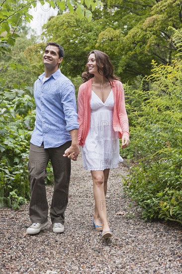 Happy couple walking through garden. Photo : Tetra Images