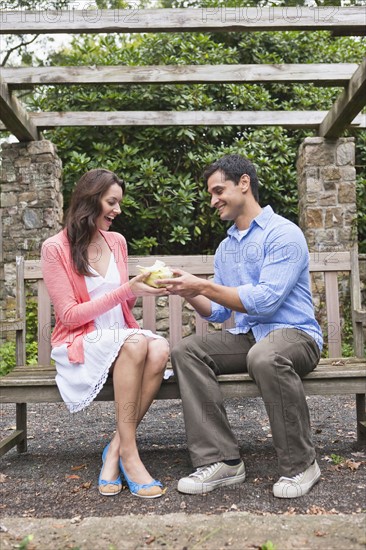 Smiling man giving gift to woman in garden. Photo : Tetra Images