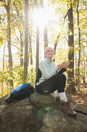 Female hiker using digital tablet in forest. Photo : Tetra Images