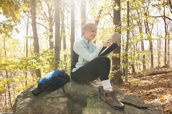Female hiker using digital tablet in forest. Photo: Tetra Images