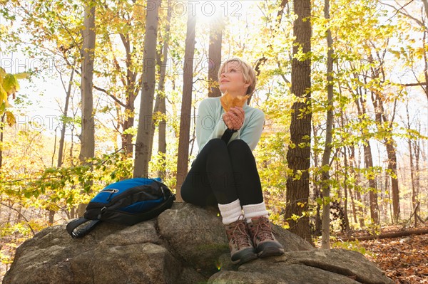 Female hiker resting on rock in forest. Photo : Tetra Images