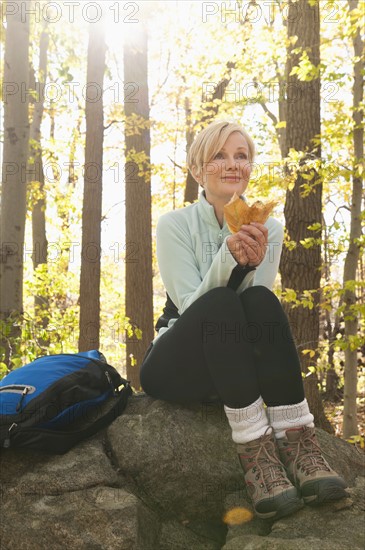 Female hiker resting on rock in forest. Photo : Tetra Images
