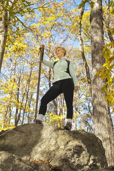 Female hiker resting on rock in forest. Photo : Tetra Images