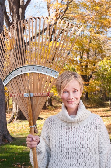 Portrait of smiling woman with rake. Photo : Tetra Images