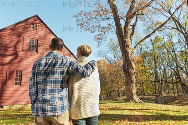 Rear view of couple facing cottage house. Photo : Tetra Images