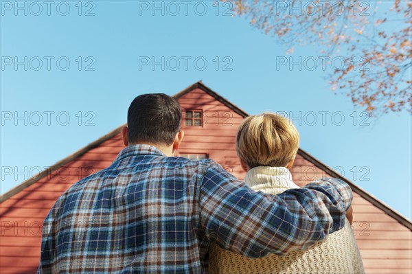 Rear view of couple facing cottage house. Photo : Tetra Images