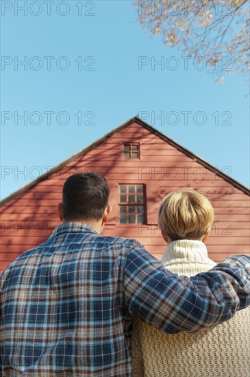 Rear view of couple facing cottage house. Photo : Tetra Images