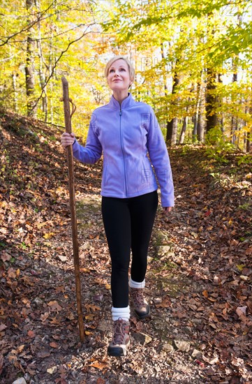 USA, New Jersey, Smiling woman hiking in Autumn forest. Photo: Tetra Images