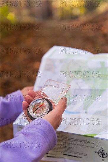 USA, New Jersey, Close-up of woman's hands holding compass and map. Photo: Tetra Images