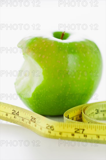 Green apple with tape measure.