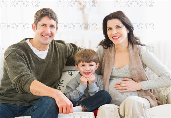 Portrait of parents with son (4-5) on sofa.