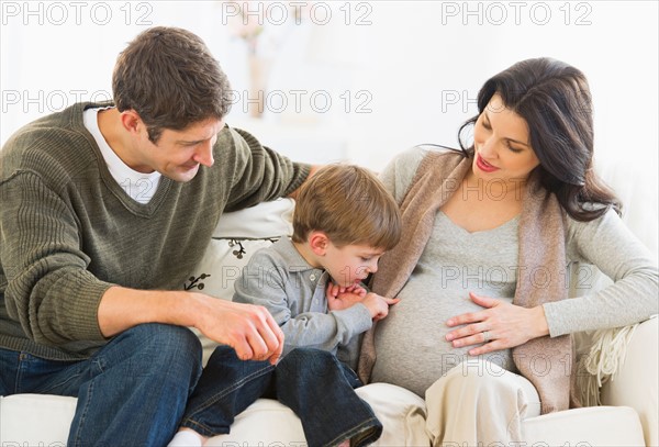 Boy (4-5) touching pregnant mother's belly.