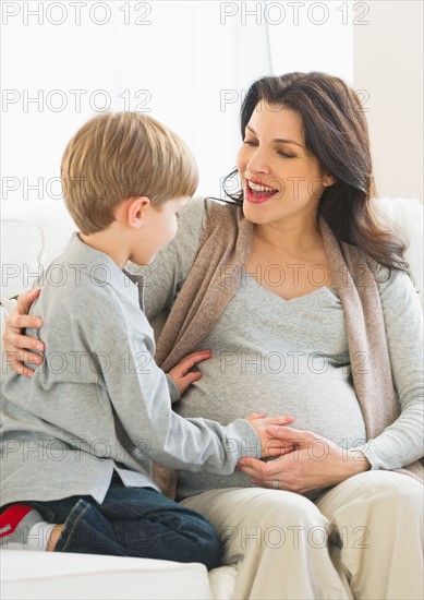 Boy (4-5) touching pregnant mother's belly.